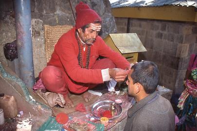 Hier erteilt ein Brahmane der Stirn eines Pilgers das rote Segenszeichen. Seine eigene Stirnbemalung erweist ihn als Anhänger Shivas Hier erteilt ein Brahmane der Stirn eines Pilgers das rote Segenszeichen. Seine eigene Stirnbemalung erweist ihn als Anhänger Shivas